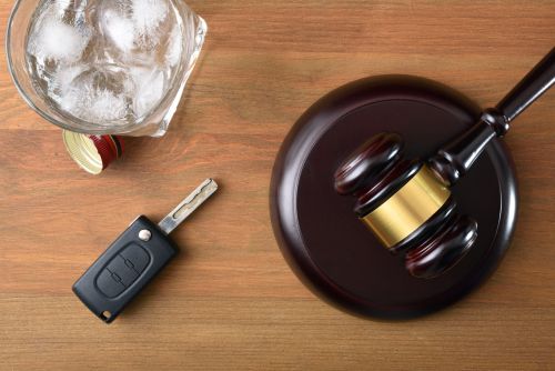 Gavel, car key and glass with alcohol on wooden table - dui penalties concept